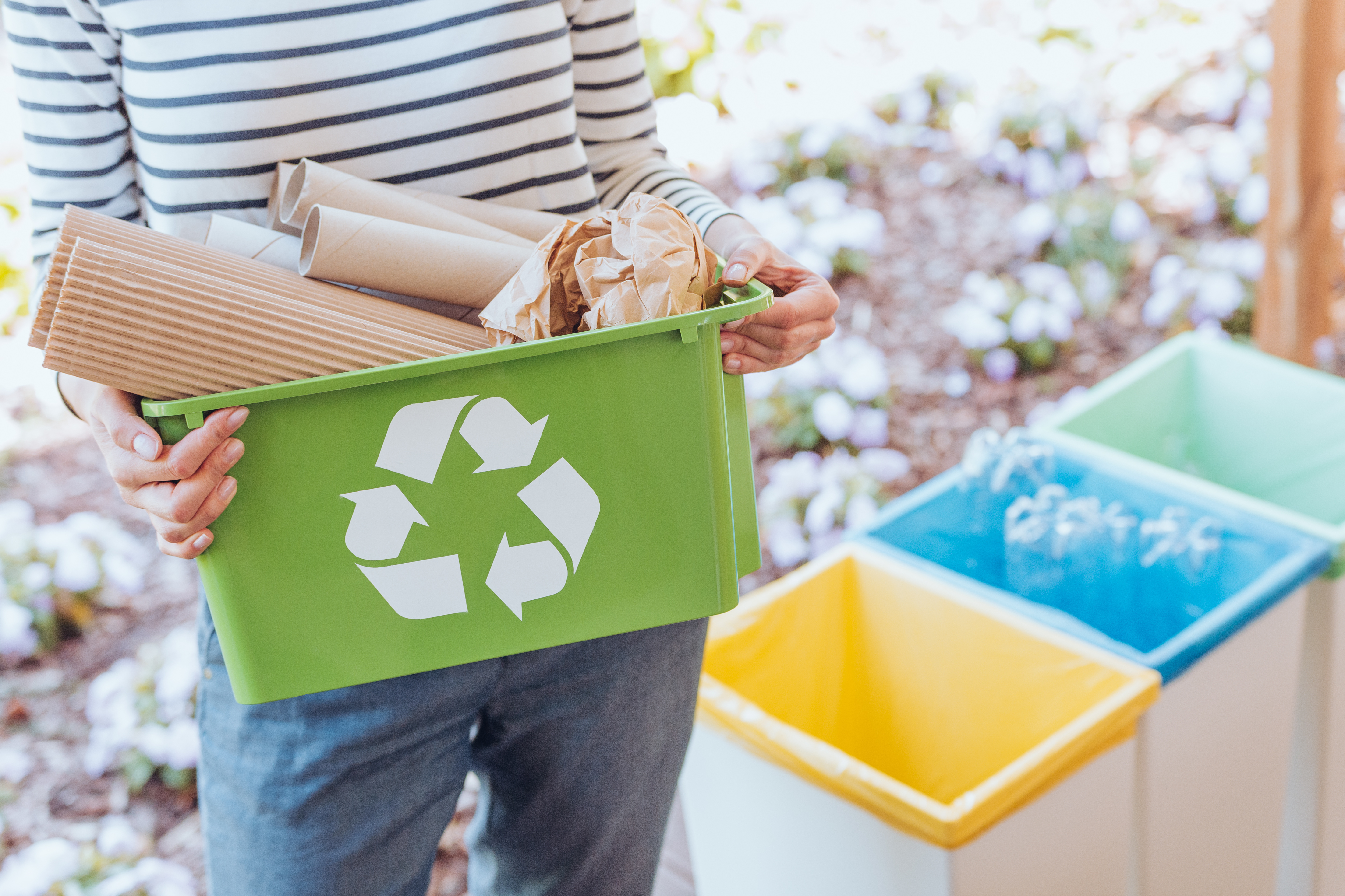 Une personne transporte un bac de recyclage résidentiel.